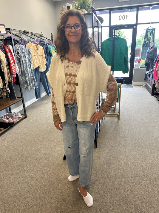 Woman standing in a store with clothing racks and displays in the background