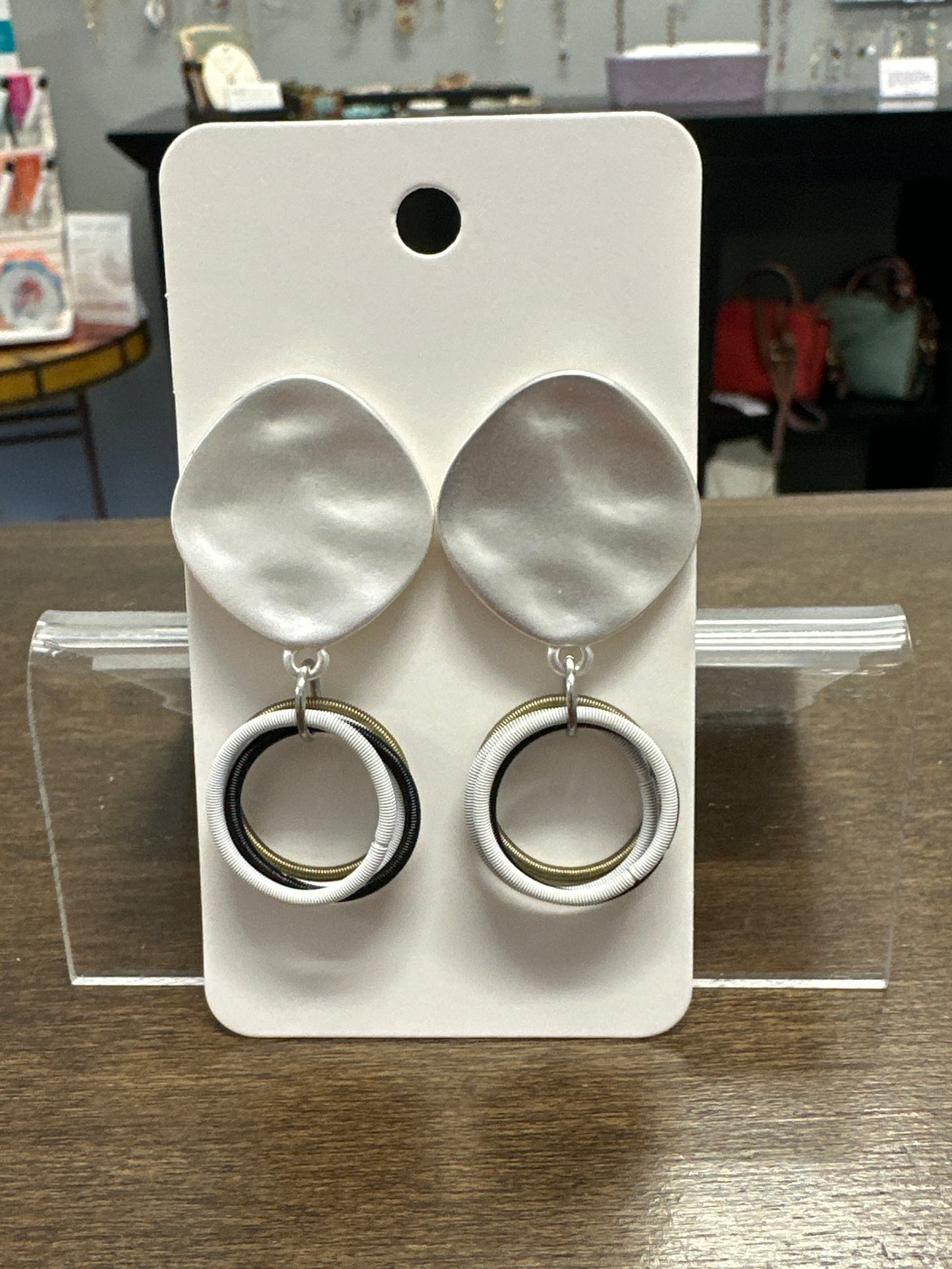 White jewelry display tray with silver rings on a wooden surface