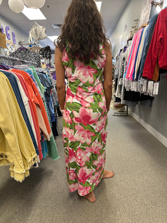 Person wearing a floral dress standing in a clothing store with racks of clothes.