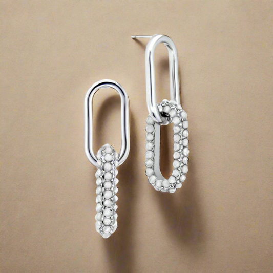 Pair of silver earrings on a beige background