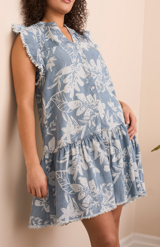 Woman wearing a blue floral dress against a beige wall