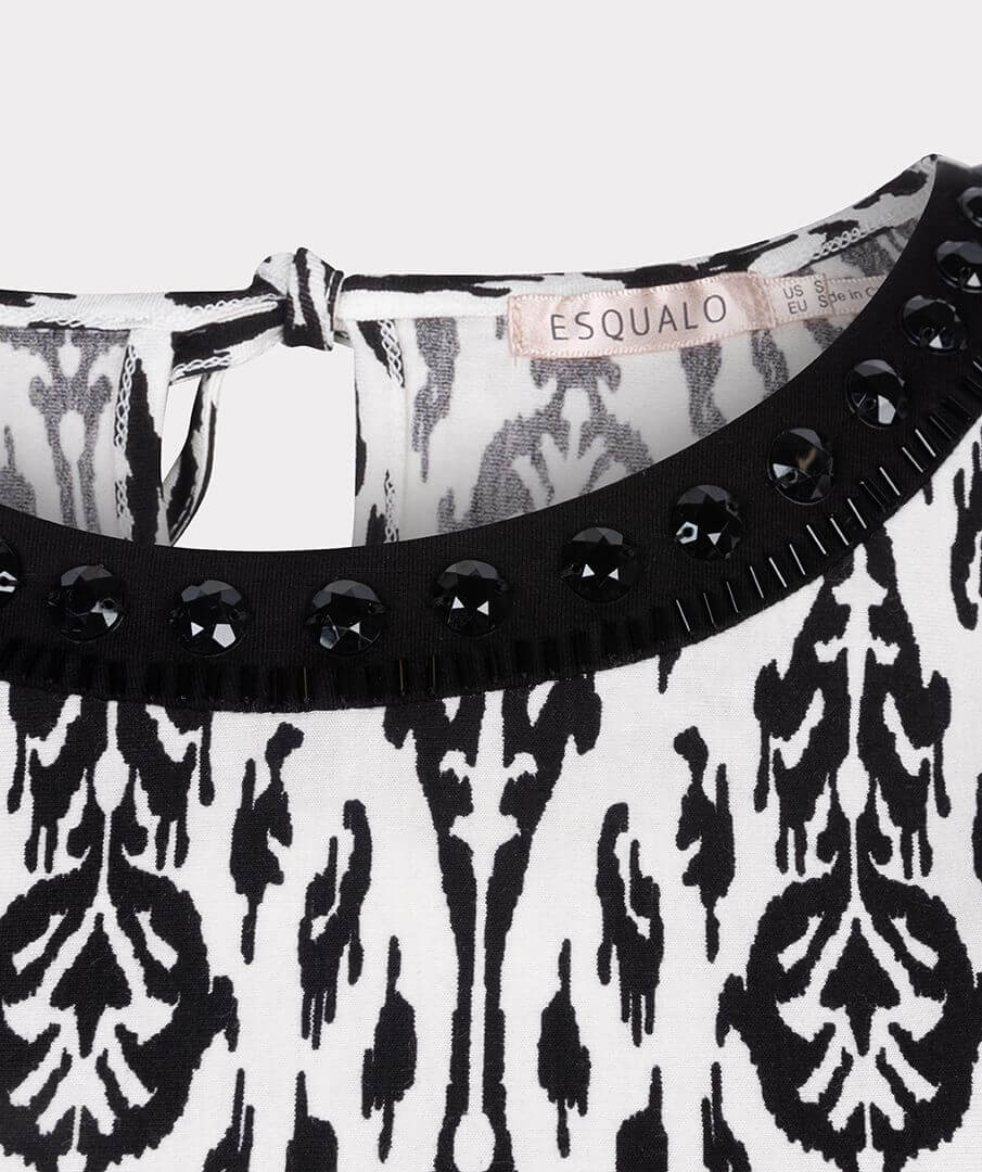 An elegant sleeveless top with tie detail at the back and pretty beads around the neckline. Easy to combine with neat pants, skirts or jeans worn tucked in or out.