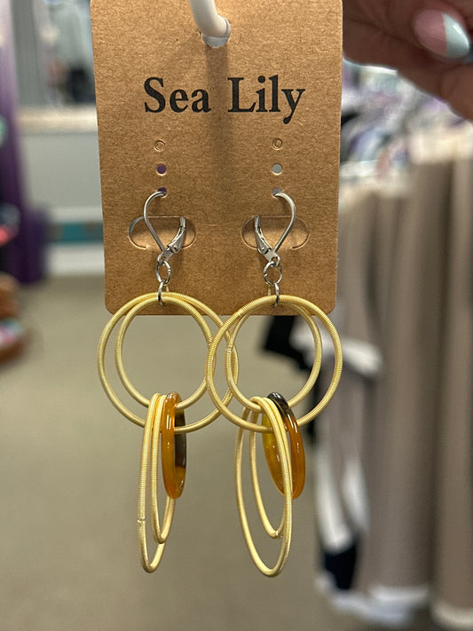 Gold hoop earrings on a Sea Lily branded card with a blurred background