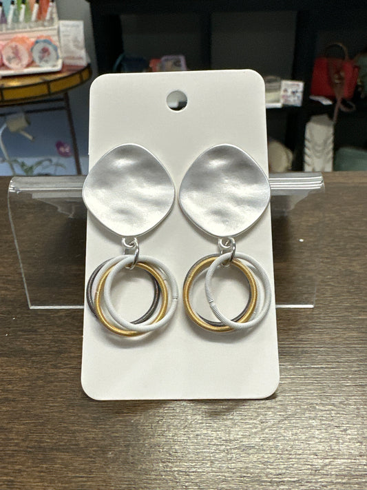 Pair of silver earrings on a white card with a blurred background