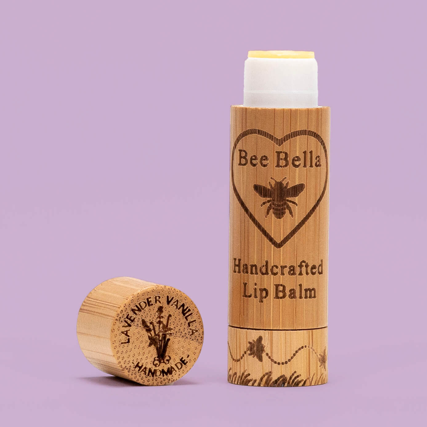 A tube of Bee Bella handcrafted lip balm in pumpkin spice flavor, placed next to a piece of sustainably sourced bamboo which is not pictured.