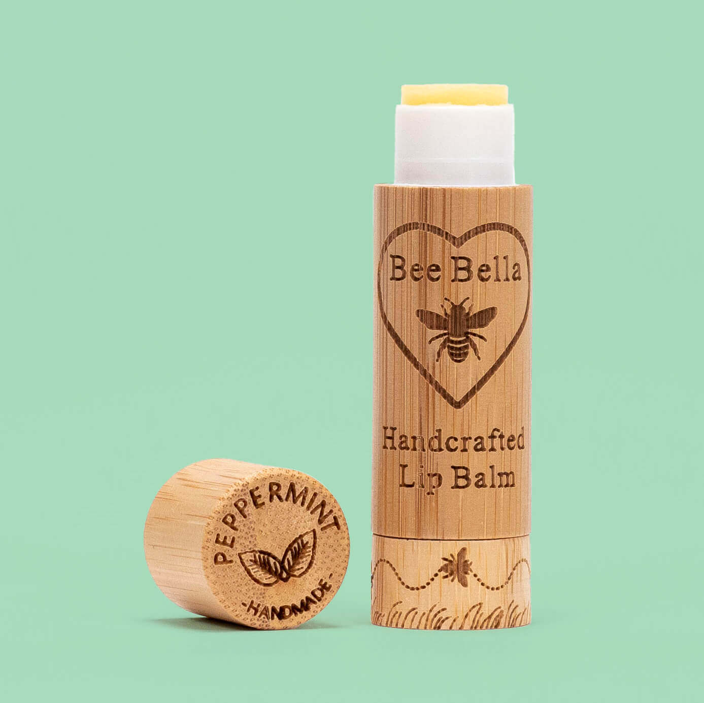 A tube of Bee Bella handcrafted lip balm in pumpkin spice flavor, placed next to a piece of sustainably sourced bamboo which is not pictured.
