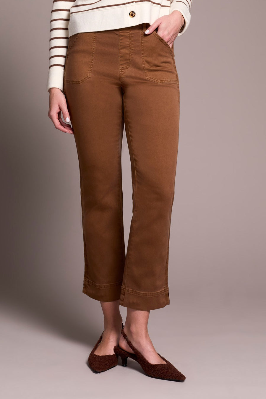 Person wearing brown pants and brown shoes on a plain background